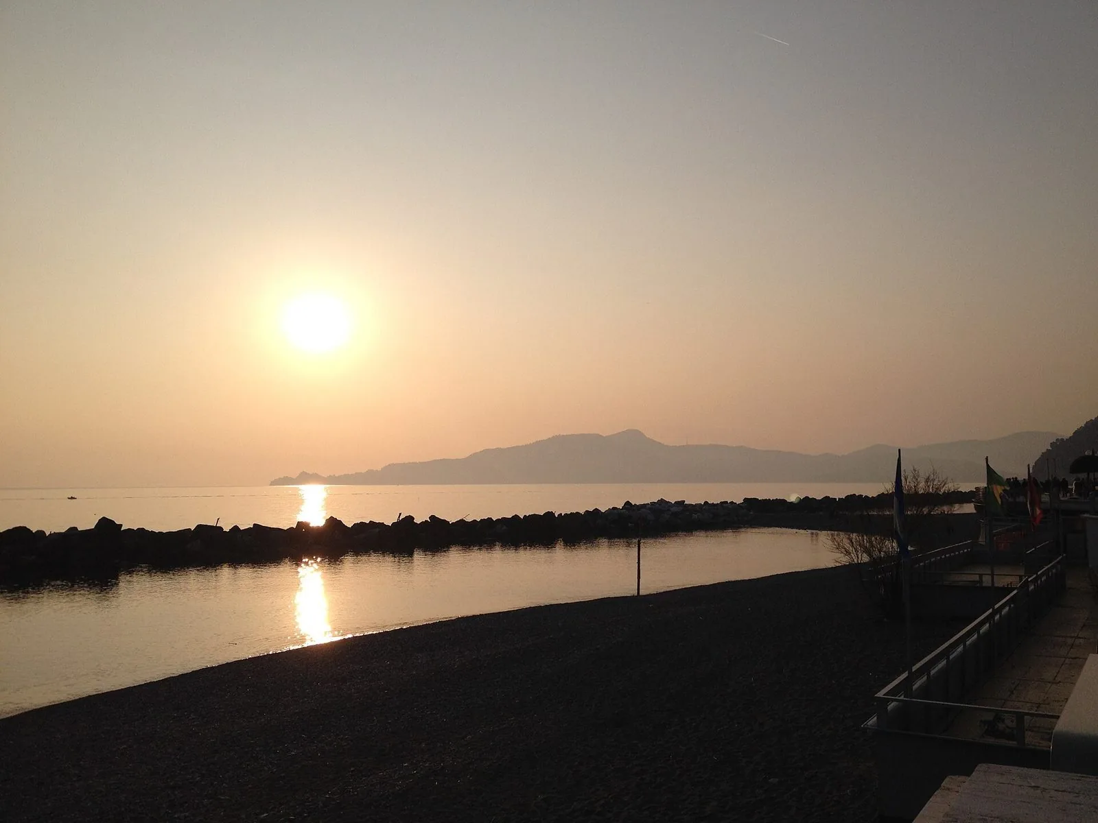Spiaggia di Chiavari deserta al tramonto con il promontorio di Portofino sullo sfondo