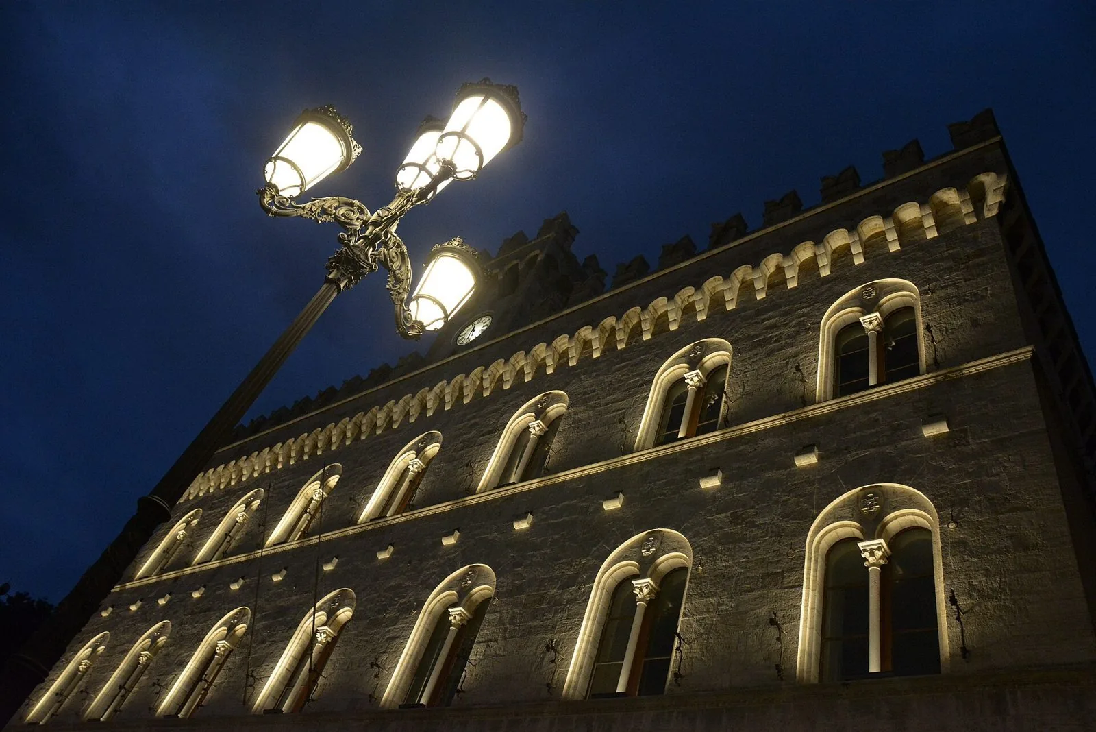 Facciata merlata del Palazzo di Giustizia di Chiavari illuminata di sera, con bifore e un lampione in ghisa